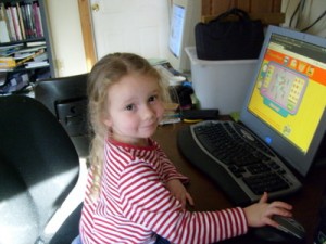 My daughter, K, using the computer to play on the Curious George website