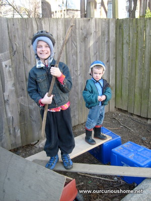 The boys dressed warmly with bicycle helmets on recycling bins and boards