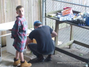 M making faces while sanding with Dad