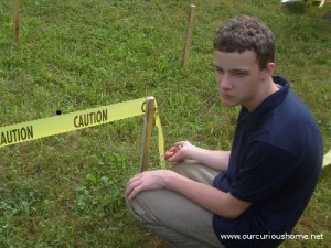 Ben staples caution tape to wooden stakes.