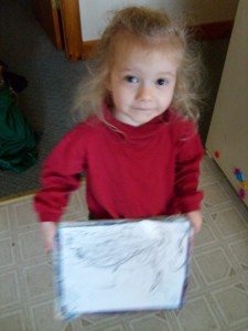 K showing the camera the white board drawing she did during M's school