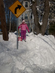 K standing on a mound of snow nearly as high as the turn sign