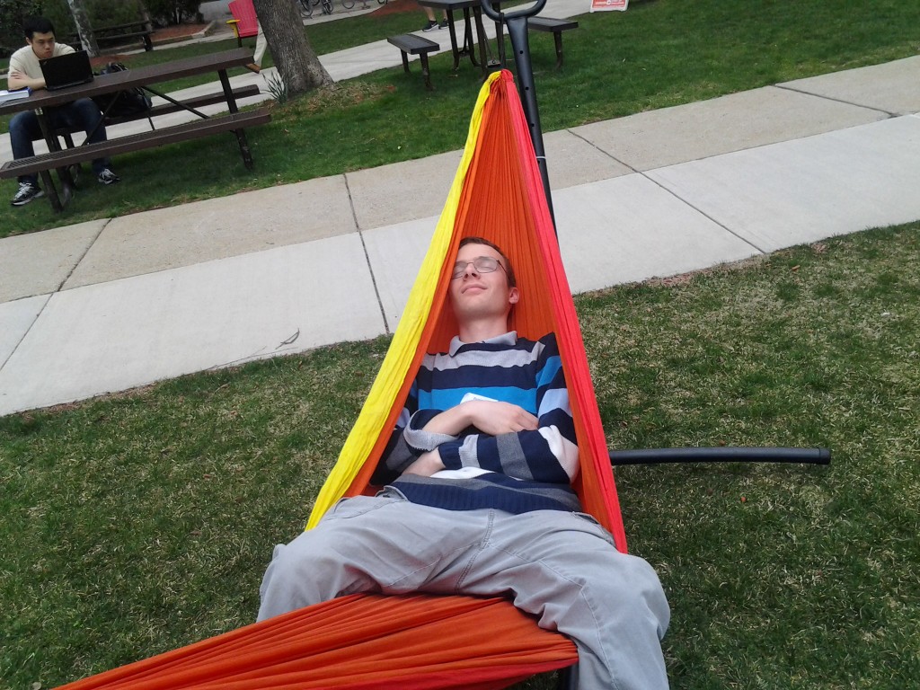 Benjamin, in a hammock, practices being a hard working student on the quad.