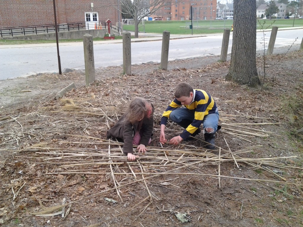 M and K begin constructing a raft from a pile of reeds.