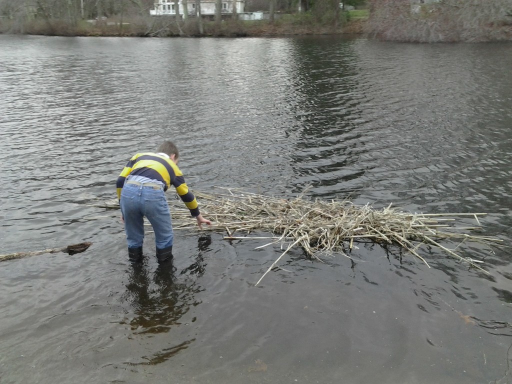 M stands in the water, examining the raft