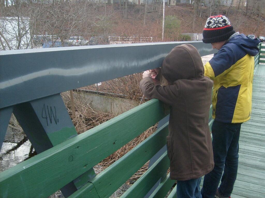 M and K sailing the paper boat off the foot bridge