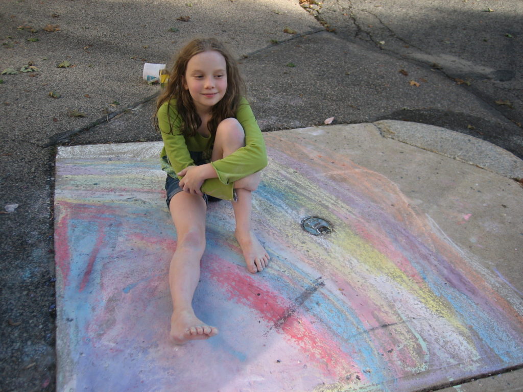 K sitting on sidewalk chalk rainbow