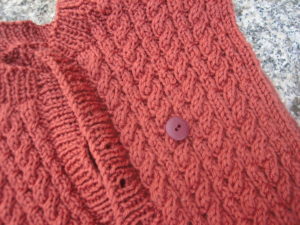 button on top of partially knit sweater