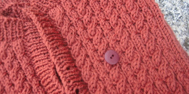 button on top of partially knit sweater